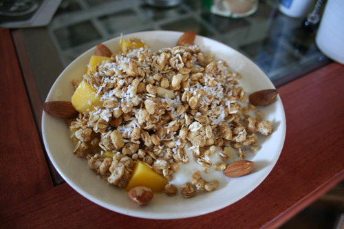 A delicious bowl of Zoe's Honey Almond granola with extra almonds and mango over yogurt.